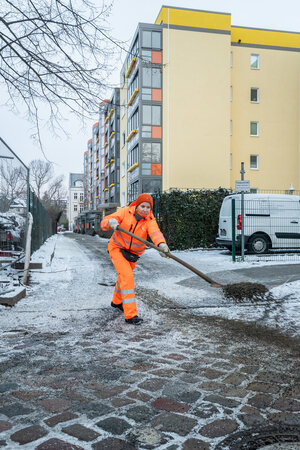 BSR Winterdienstkraft beim Streuen eines Überwegs