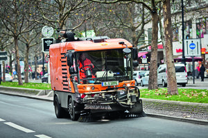 Mittelgroße Kehrmaschine der BSR reinigt Fahrbahn.