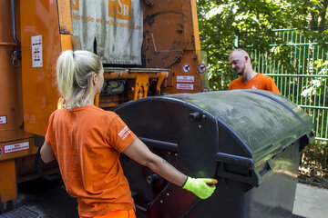 BSR-Müllwerkerin lädt mit ihrem Kollegen lädt Müll in Müllwagen