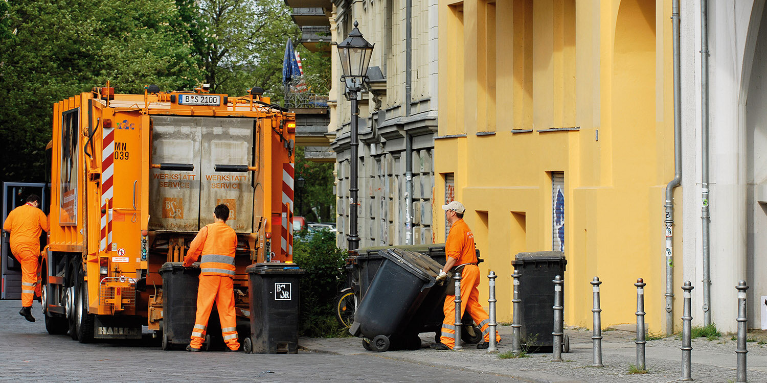 Müllwerker zieht Tonnen an ein Müllsammelfahrzeug